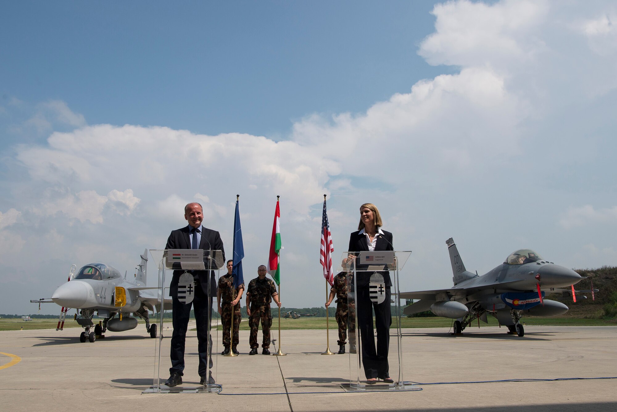 Dr. Simicsko Istvan, Hungarian Minister of Defense and Colleen Bell, U.S. Ambassador to Hungary, speak to American and Hungarian troops at Pápa Air Base, Hungary during Panther Strike 2016, July 27, 2016. A Hungarian Gripen and an American F-16 were both used during the multinational training event and can be seen in the background. Istvan and Bell were amongst the senior officials in attendance for distinguished visitor day, all of whom received an opportunity to tour the base, speak with individuals participating in the training mission and and see the aircraft involved. (U.S. Air National Guard photo by Senior Master Sgt. John Rohrer)