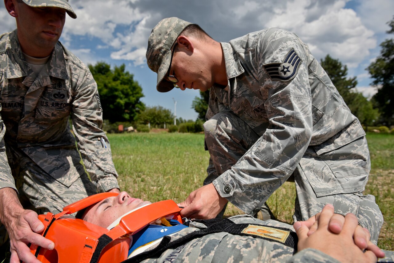 Staff Sgt. Corey Czajka tightens the straps to hold head blocks in place during a long backboard training exercise at Peterson Air Force Base, Colo., July 28, 2016. Czajka used his medical training during a recent real-world incident when he kept an injured patient conscious and stable, then continued to assist after paramedics arrived. Air Force photo by Senior Airman Rose Gudex

