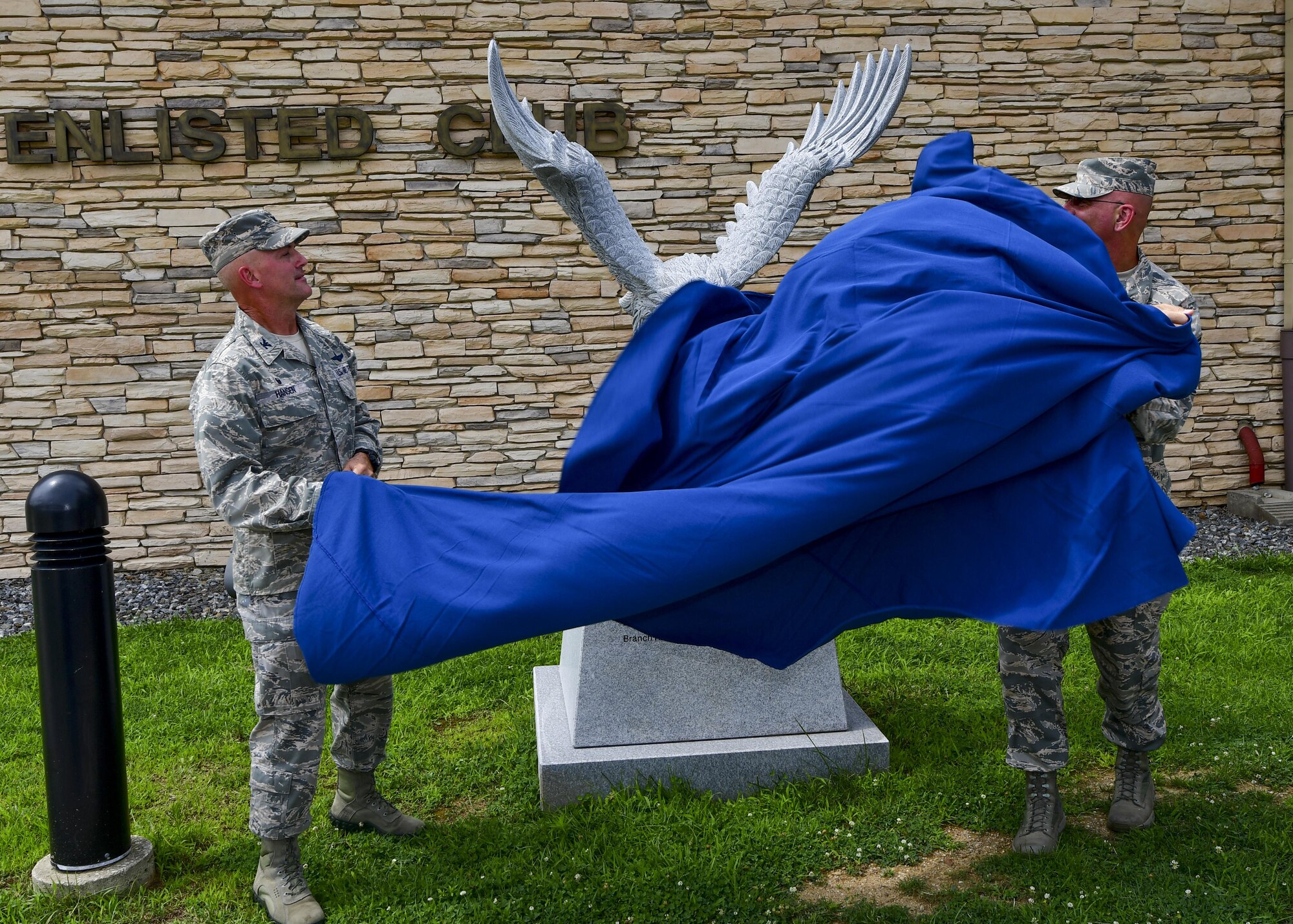 Col. Andrew Hansen, 51st Fighter Wing commander, and Chief Master Sgt. Alex Del Valle, 51st Fighter Wing command chief, unveil the new eagle statue dedicated to retired Master Sgt. Jim Price outside of the base enlisted club at Osan Air Base, Republic of Korea, Aug. 1, 2016. The previous eagle statue was damaged in the fall of 2015, and was replaced with a larger, more detailed statue thanks largely to the efforts and contributions of the Osan Chief’s Group, Team Osan Spouses Club, and the 731st Air Mobility Squadron. (U.S. Air Force photo by Senior Airman Victor J. Caputo/Released)