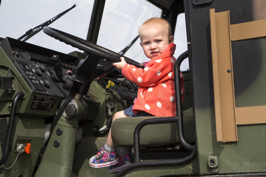 A 16-month-old sits at the wheel of an Army truck 