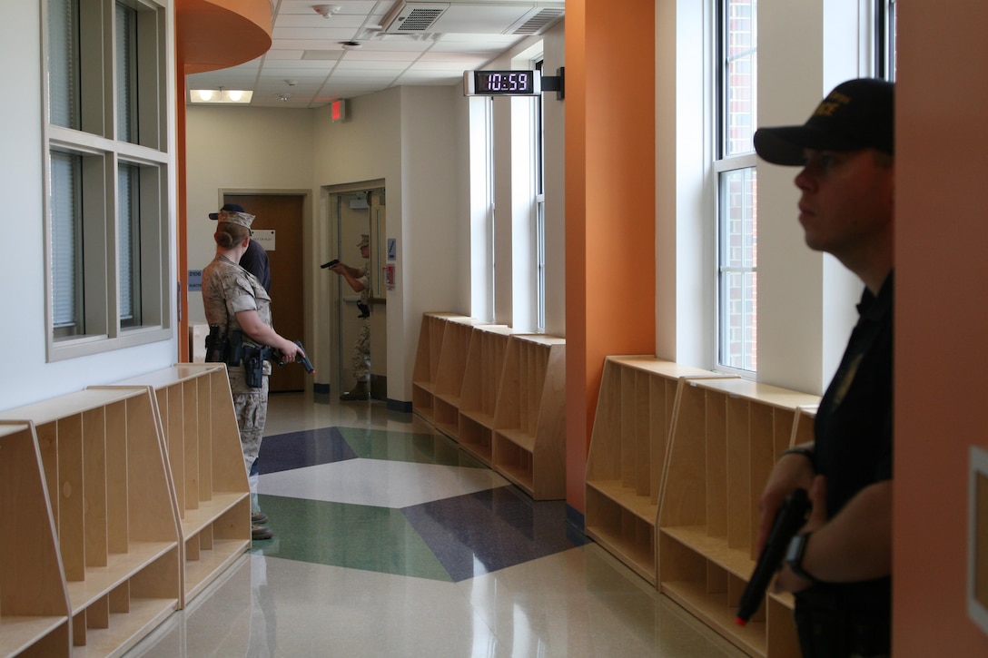 Marine MPs and civilian law enforcement guard a hallway in Crossroads Elementary School while hostage negotiators attempt to neutralize an active shooter threat during a drill conducted July 27 aboard Marine Corps Base Quantico.