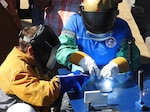 SAN DIEGO, Calif (Aug. 2, 2016) Ms. Travie Ross, daughter of Hershel Woodrow "Woody" Williams, welds her initials into the ship's keel during a keel laying ceremony for the future USNS Hershel "Woody" Williams (ESB 4) in San Diego, California, Aug 2. Hershel Woodrow "Woody" Williams is the last living Medal of Honor recipient from the Battle of Iwo Jima. PEO Ships is responsible for executing the development and procurement of all destroyers, amphibious ships, special mission and support ships, boats and craft.