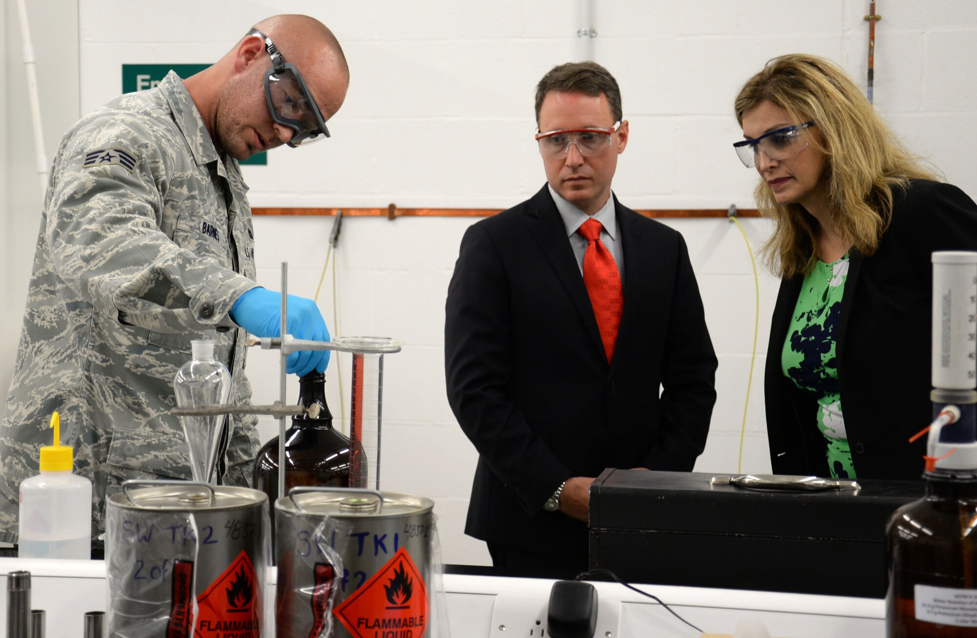 U.S. Air Force Senior Airman Nickolaus Barnes, left, 100th Logistics Readiness Squadron fuels laboratory technician, shows Amanda Simpson, right, Deputy Assistant Secretary of Defense for Operational Energy, and Robert Warshel, center, Director of Operations, Operational Energy Plans and Programs, how shop personnel ensure only clean fuel is given to aircraft during a briefing on the bottle method test July 29, 2016, on RAF Mildenhall, England. Barnes explained how he looks for particulates in the fuel through filtration which allows him to monitor and minimize contamination in a fuel system. (U.S. Air Force photo by Gina Randall)