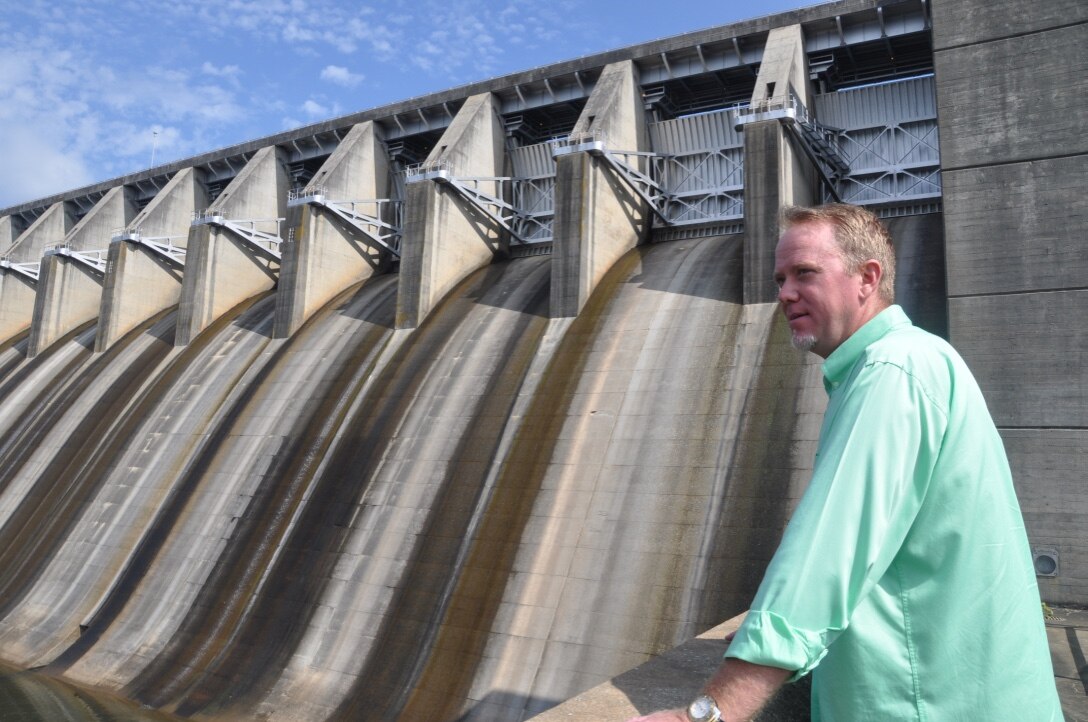 Operator Trainee Les Rice poses before Thurmond Dam's spillway gates July 6. Rice is a 4th-year operator trainee in the Savannah District's Operator Training Program. The competitive program accepts only an elite crop of qualified candidates who must endure 4-5 years of demanding requirements surrounding dam operations.