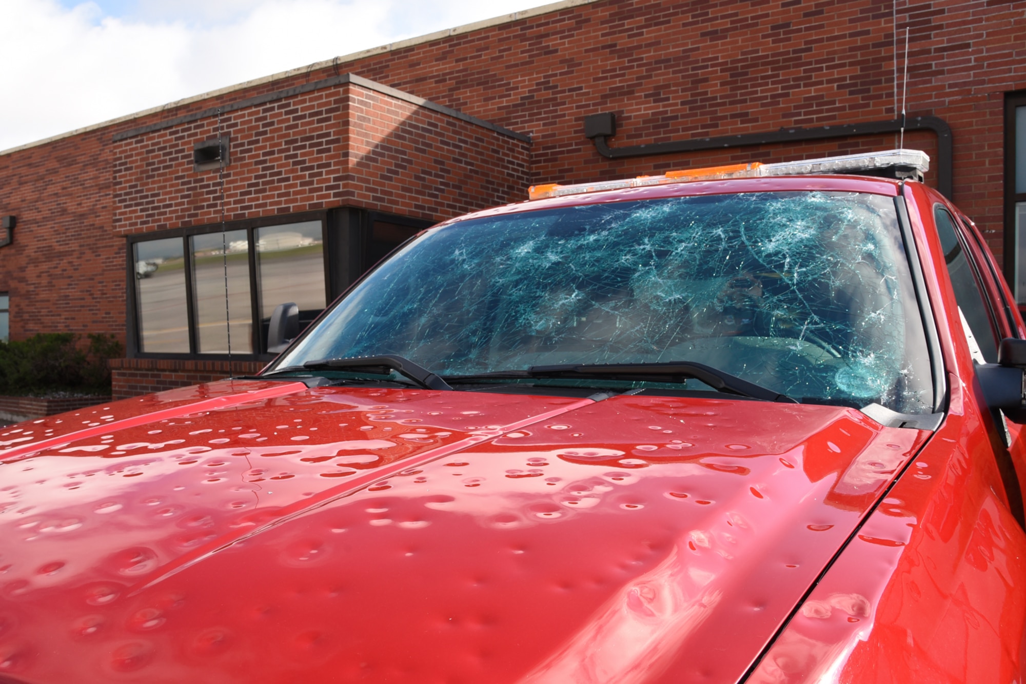 Damaged vehicles sit in parking lots at Peterson Air Force Base, Colo., Aug. 1, 2016. Peterson AFB was hit by a storm carrying hail the size of baseballs. (U.S. Air Force photo by Airman 1st Class Dennis Hoffman)