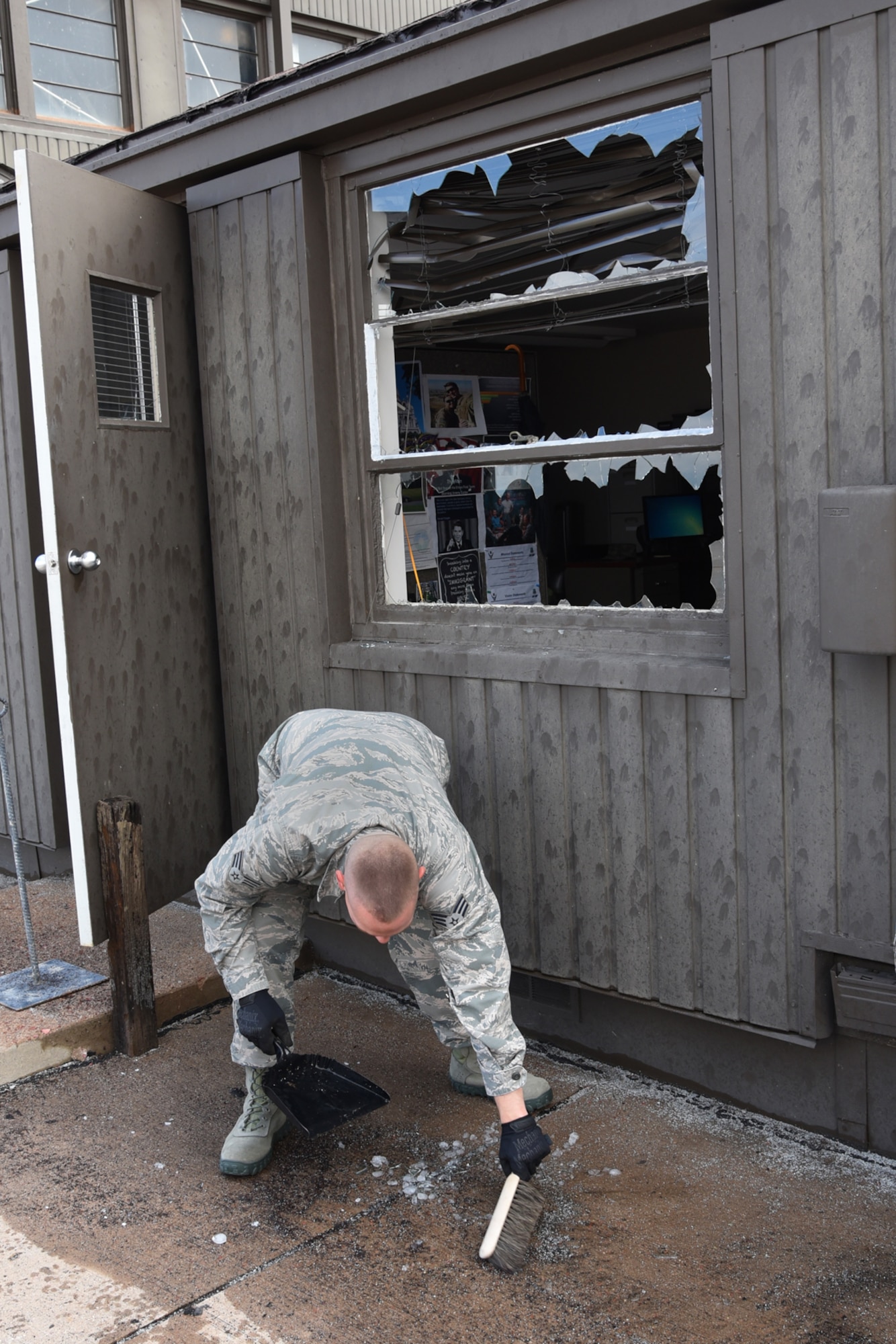 Airman cleans up broken glass at Peterson Air Force Base, Colo., Aug. 1, 2016. Peterson AFB was hit by a storm carrying hail the size of baseballs. (U.S. Air Force photo by Airman 1st Class Dennis Hoffman)