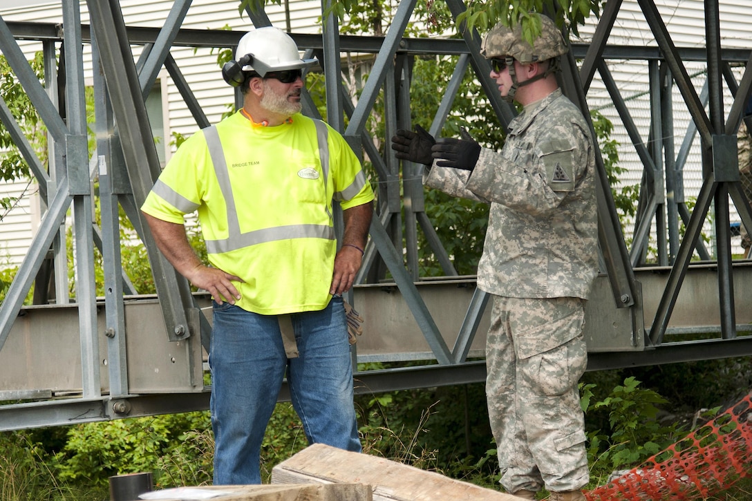 Hobie Gates, a special project supervisor for the bridge crew, Vermont Agency of Transportation and a Connecticut Army National Guardsman discuss the assembly of a Mabey Logistic Support Bridge as part of a simulated bridge collapse during the Vigilant Guard 2016 training exercise in Berlin, Vt., July 29, 2016. Air National Guard photo by Tech. Sgt. Chelsea Clark