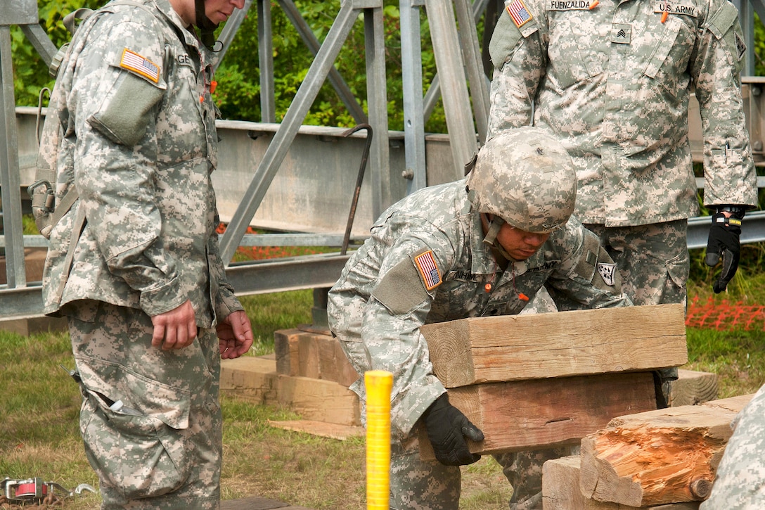 A Connecticut Army National Guardsman lifts several large pieces of wood to be used in the assembly of a Mabey Logistic Support Bridge as part of a simulated bridge collapse during the Vigilant Guard 2016 training exercise in Berlin, Vt., July 29, 2016. Air National Guard photo by Tech. Sgt. Chelsea Clark 