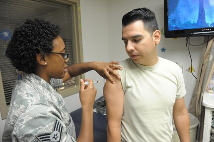 Staff Sgt. Tiffany Jones, 359th Medical Group, Immunization Clinic, immunizes Capt. Israel Brito, July 28, 2016, during Immunization Awareness Month at Joint Base San Antonio-Randolph.  Immunization Awareness Month provides an opportunity to highlight the value of immunization across the lifespan.  Activities focus on encouraging all people to protect their health by being vaccinated against infectious diseases. 