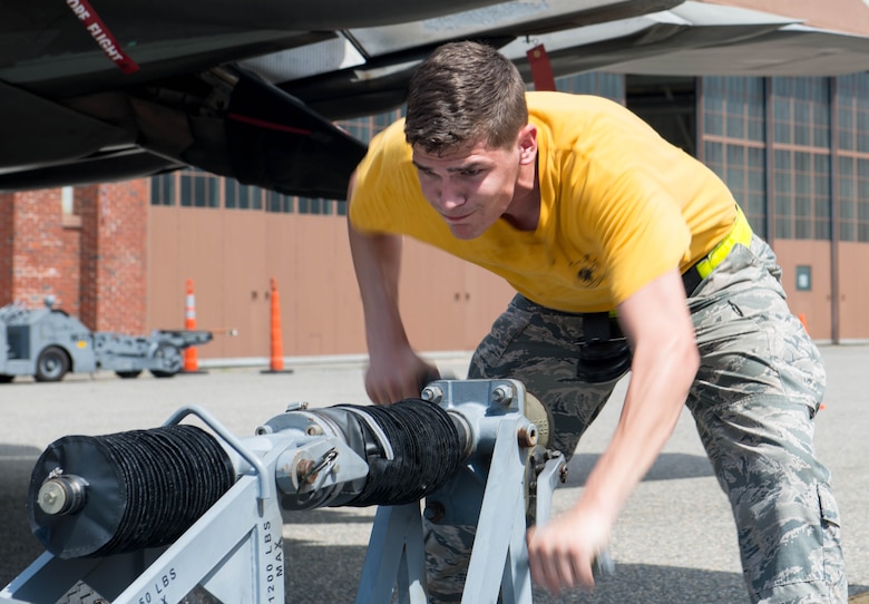 U.S. Air Force Senior Airman Trenton Miclette, 94th Aircraft Maintenance Unit maintainer, cranks a manually operated lift truck during the 1st Maintenance Squadron Weapons Load Crew of the Quarter competition at Langley Air Force Base, Va., July 29, 2016. The teams used the lift truck to load a GBU-32, a Joint Direct Attack Munition which weighs more than 1,000 pounds.  (U.S. Air Force photo by Staff Sgt. R. Alex Durbin)