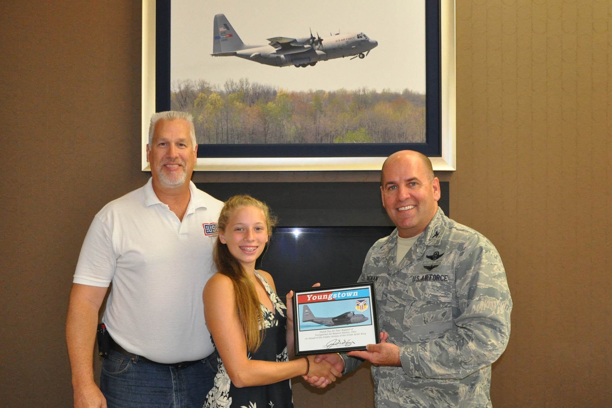 Col. James Dignan (right), 910th Airlift Wing commander, and Bruce Bille (right), Second Vice President of the USO of Northern Ohio, present a certificate of appreciation to Olivia Vaupel (center) at the Community Activity Center here,  July 21, 2016. In 2014, Vaupel asked her family to donate items to Servicemembers serving locally and overseas instead of giving her a birthday present and gifts. Bille arranged for Vaupel, her mother and a small group of Olivia’s family and friends to visit YARS for a lunch with Dignan, the certificate presentation and a tour of the installation and a C-130H Hercules cargo aircraft in appreciation for the youth’s efforts. (U.S. Air Force photo/Master Sgt. Bob Barko Jr.)