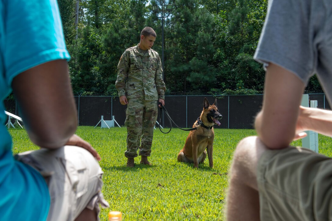 PFC Brendan Trapp, 3rd Military Police Detachment K-9 military working dog handler, demonstrates different military working dog commands for the Youth Leadership Alliance of the Virginia Peninsula Chamber Foundation at Fort Eustis, Virginia, August 1, 2016. While at the K-9 compound, the group spoke to 733rd Security Forces Squadron leadership about different experiences of military police. (U.S. Air Force photo by Staff Sgt. J.D. Strong II)