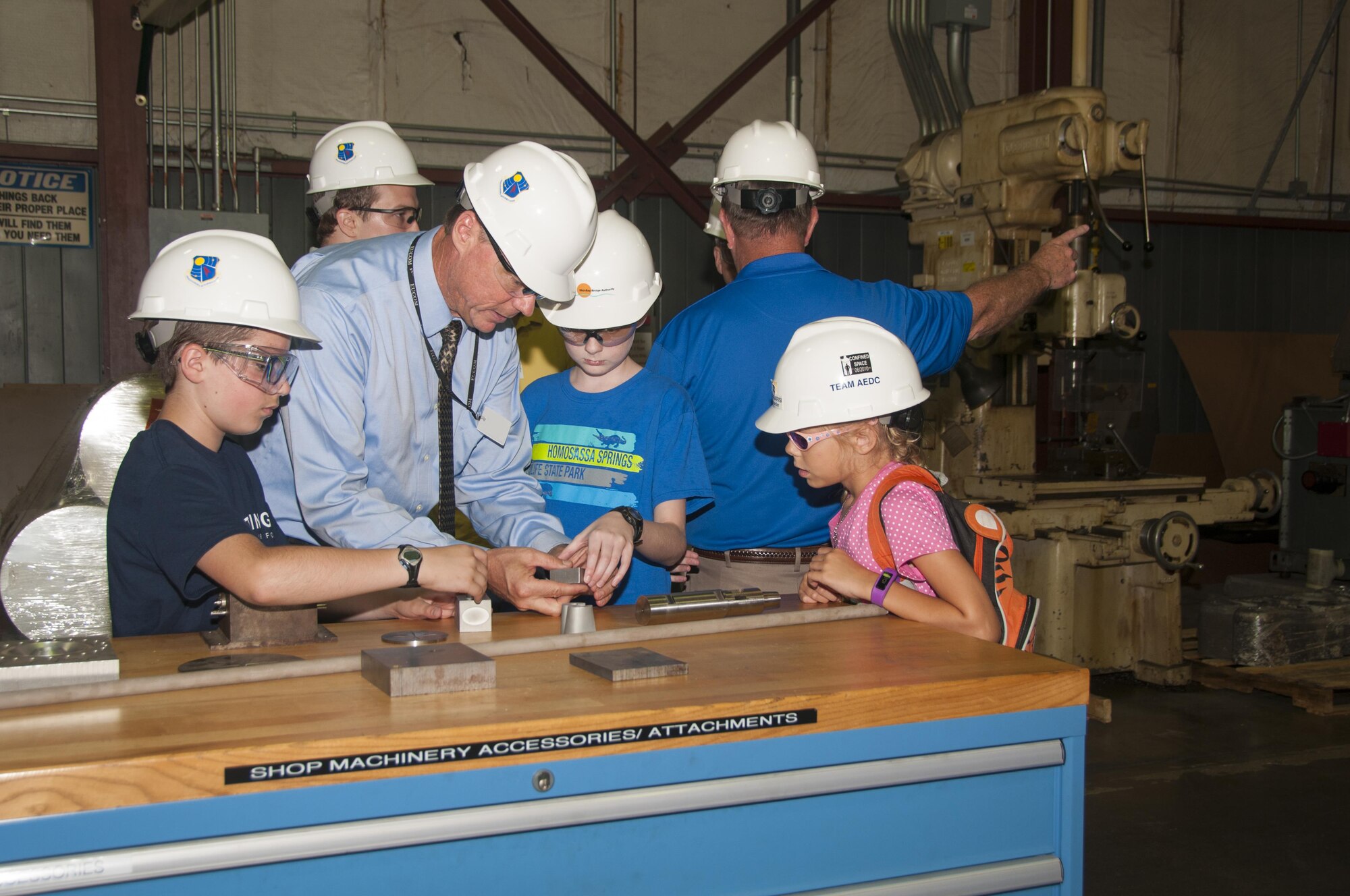 Michael Panarisi, retired Air Force colonel and former AEDC Commander, tours the AEDC Model and Machine Shop with his family as Model Shop staff work to complete a project for the Advanced Precision Kill Weapon Systems (APKWS) Program Office. Panarisi, second from left, assisted the APKWS Program Office by recommending the Model Shop complete its time sensitive request. Pictured are Calder Smith, Michael Panarisi, Michael Panarisi Jr., and Reanna Panarisi looking at items fabricated by the AEDC Machine Shop. (U.S. Air Force Photo/Holly Peterson)