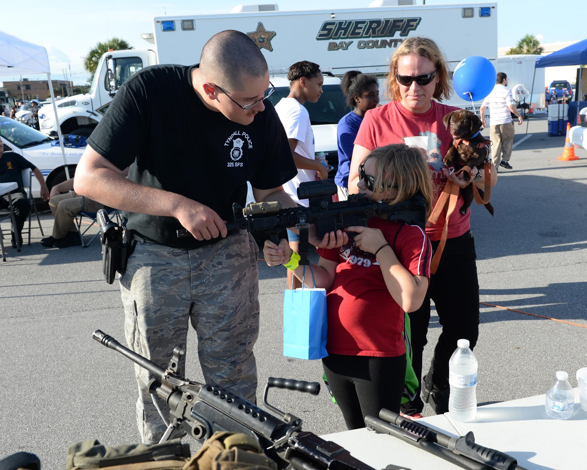 U.S. Air Force Senior Airman Caleb Imel, 325th Security Forces Squadron response force leader, shows a child how to properly hold an M4 Carbine weapon system during National Night Out at the Panama City Mall, Fla., Aug. 2, 2016. The event is held the first Tuesday in August each year across the nation as a means to interact and foster positive relationships between emergency response departments and their communities. (U.S Air Force photo by Airman 1st Class Cody R. Miller/Released)