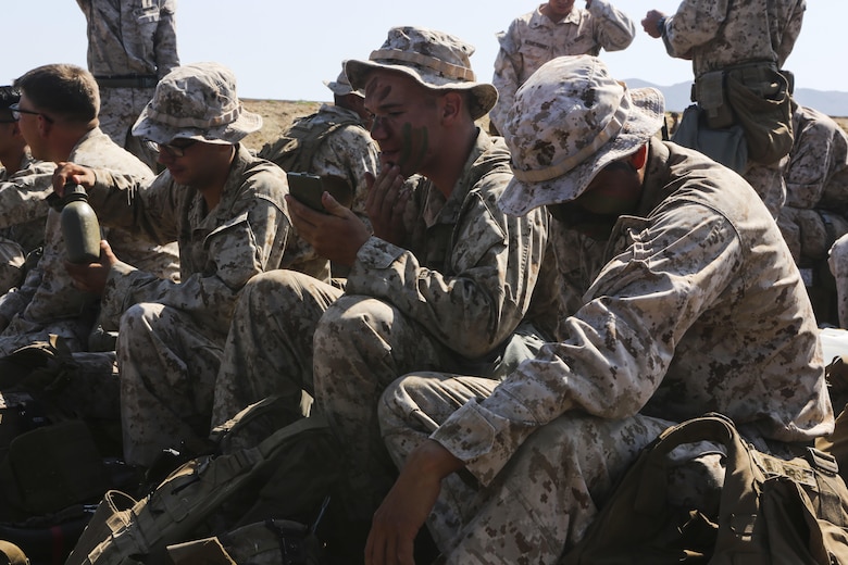 Marines with 3rd Battalion, 1st Marine Regiment apply camouflage face paint as they wait to board an aircraft during training aboard Marine Corps Base Camp Pendleton, Calif., July 28.  Marine Heavy Helicopter Squadron (HMH) 462 and the Royal Canadian Air Force supported 3rd Battalion, 1st Marine Regiment during Rim of the Pacific (RIMPAC) 2016. (U.S. Marine Corps photo by Lance Cpl. Harley Robinson/Released)