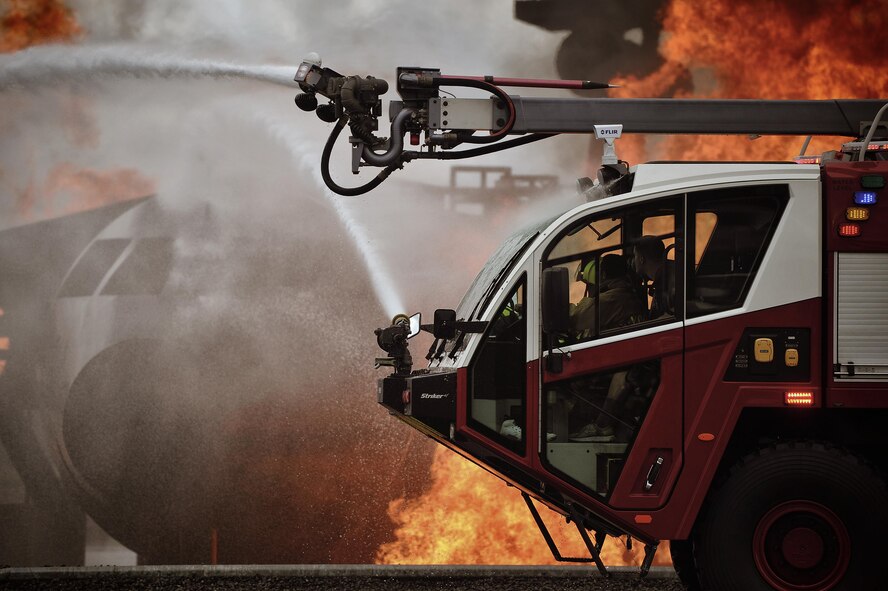 Firefighters with the 374th Civil Engineer Squadron operate a fire truck while battling a simulated aircraft fire at Yokota Air Base, Japan, Aug. 1, 2016. Yokota uses a variety of facilities to train firefighters, including aircraft, building and flashover (or suddenly-flaring) fires. (U.S. Air Force photo by Senior Airman Delano Scott/Released)