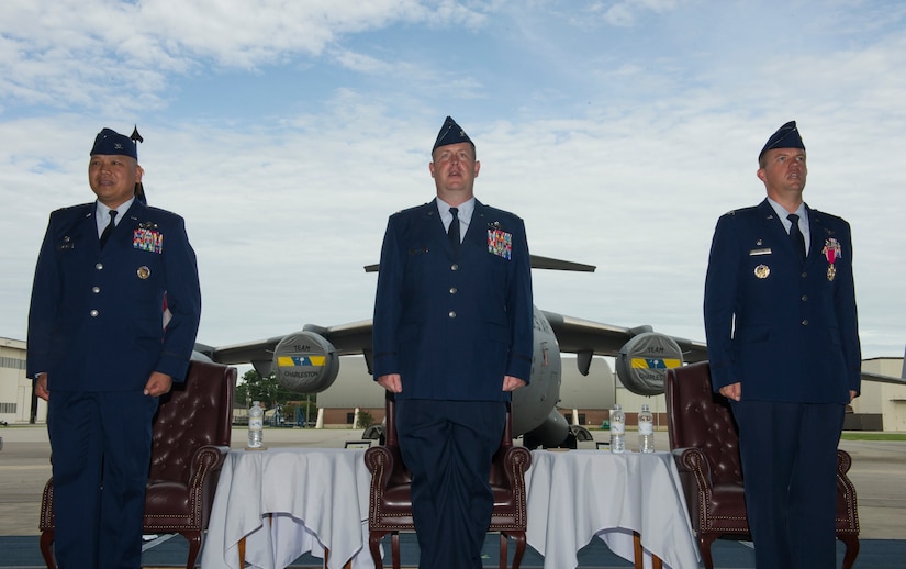 Col. Jimmy Canlas, 437th Airlift Wing (AW) commander, left, Col. Louis Hansen, 437th Operations Group (OG) commander and Col. Scovill Currin, 916th Aircraft Refueling Wing (ARW) vice commander - Seymour Johnson Air Force Base, NC, right, lead the audience in singing the Air Force song in Nose Dock 2, Joint Base Charleston – AB, Charleston, SC, for a change of command ceremony on Aug. 2, 2016. The change of command was for the 437th OG where Hansen assumed command from Currin. (U.S. Air Force photo by Airman 1st Class Thomas T. Charlton)