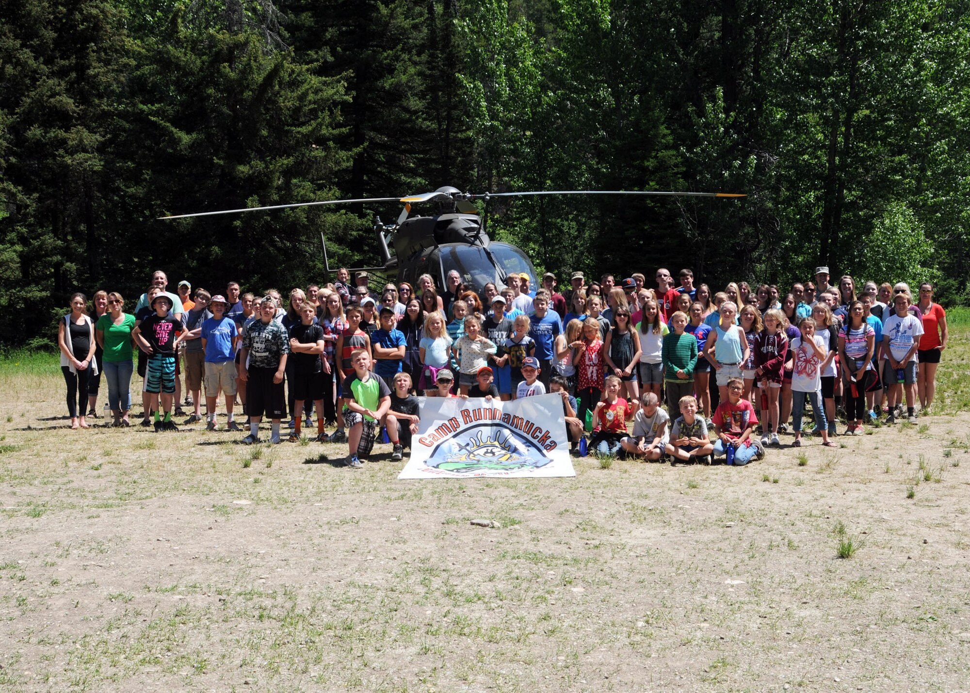 Kids and staff members pose for a group photo in front of a Montana Army National Guard helicopter during Camp Runnamucka June 29, 2016. The week-long camp is designed for children of Montana National Guard children whose parents have deployed or will soon deploy. Camp Runnamucka is held each year at Camp Rotary located near Monarch, Mont. (U.S. Air National Guard photo by Senior Master Sgt. Eric Peterson)