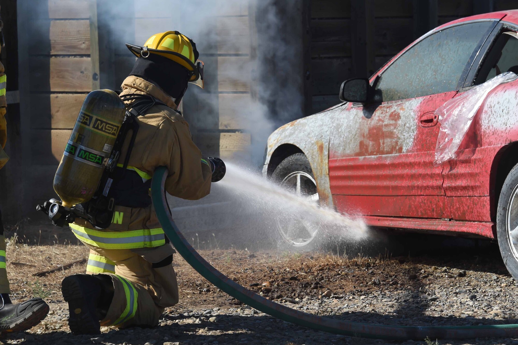 U.S. Air Force Senior Airman Abraham Barragnon, 144th Civil Engineer Squadron firefighter, puts out a simulated fire during a training exercise at the Fresno Air National Guard Base July 10, 2016. The training exercise scenario required multiple agencies to respond to the simulated emergency, to include members from 144th CES explosive ordnance disposal flight. (U.S. Air National Guard photo by Senior Airman Klynne Serrano)