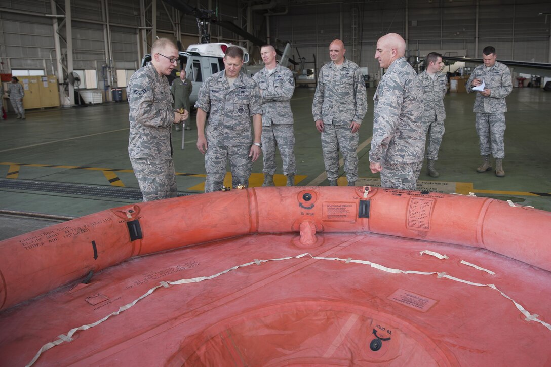 Senior Airman Zachary Cody, left, 374th Operations Support Squadron aircrew flight equipment journeyman, gives a brief description of the F-2B life raft inflating system to Brig. Gen. Michael Winkler, second from the left, 5th Air Force vice commander, during his immersion tour at Yokota Air Base, Japan, Aug. 2, 2016. Aircrew Flight Equipment specialists with the 374th Operations Support Squadron make sure aircrew have the supplies necessary for their missions. The team of AFE Airmen pack emergency items such as parachutes and survival kits and also maintain helmets and oxygen masks. (U.S. Air Force photo by Yasuo Osakabe/Released)  