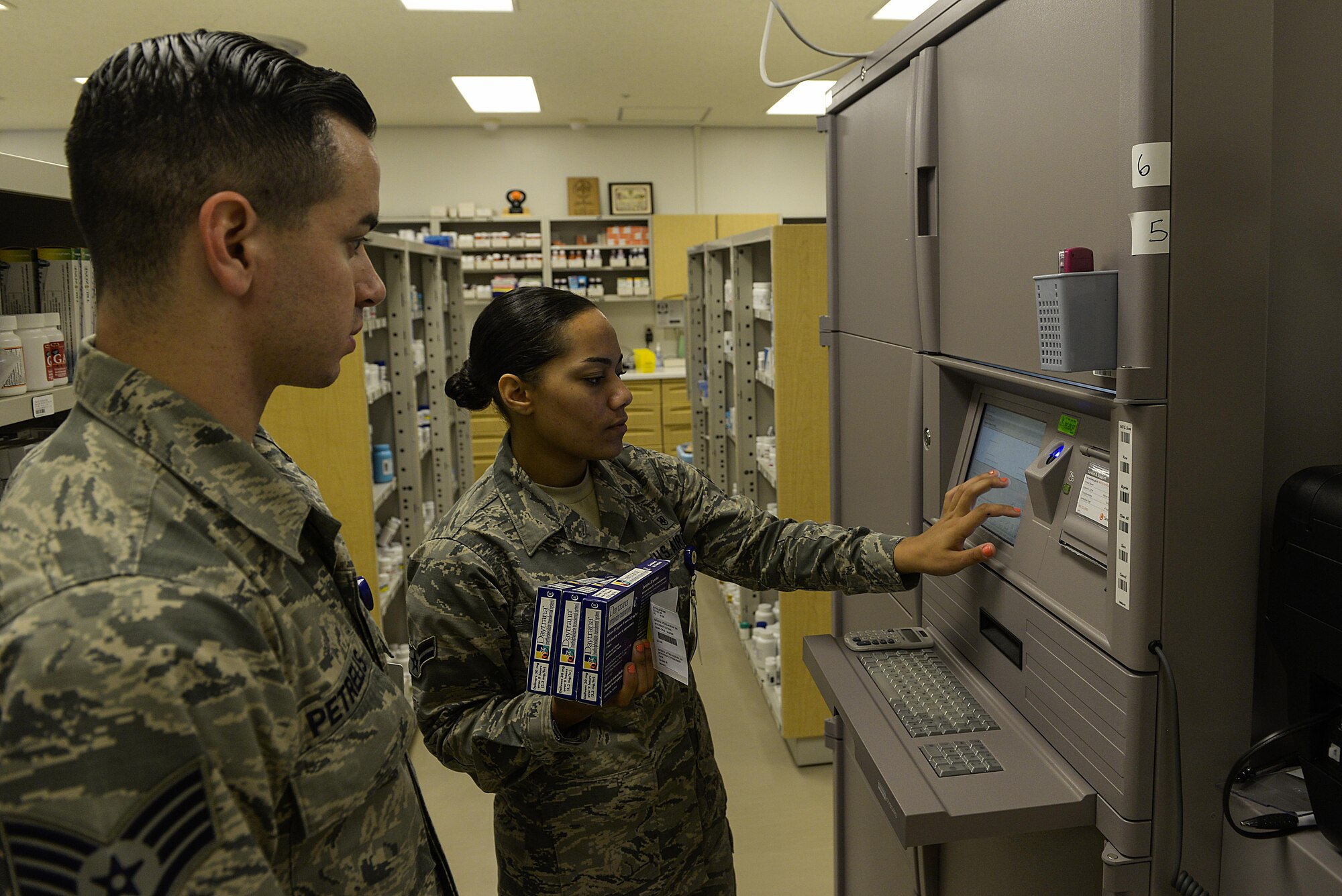 Staff Sgt. Nicholas Petrelis, 18th Medical Group pharmacy supply custodian, watches as Airman 1st Class Cheyenne Saxton, 18th MDG pharmacy journeyman, logs into the Pyxis MedStation system inside the pharmacy Aug. 3, 2016, at Kadena Air Base, Japan. The Pyxis MedStation system is an automated medication dispensing system. (U.S. Air Force photo by Senior Airman Stephen G. Eigel)