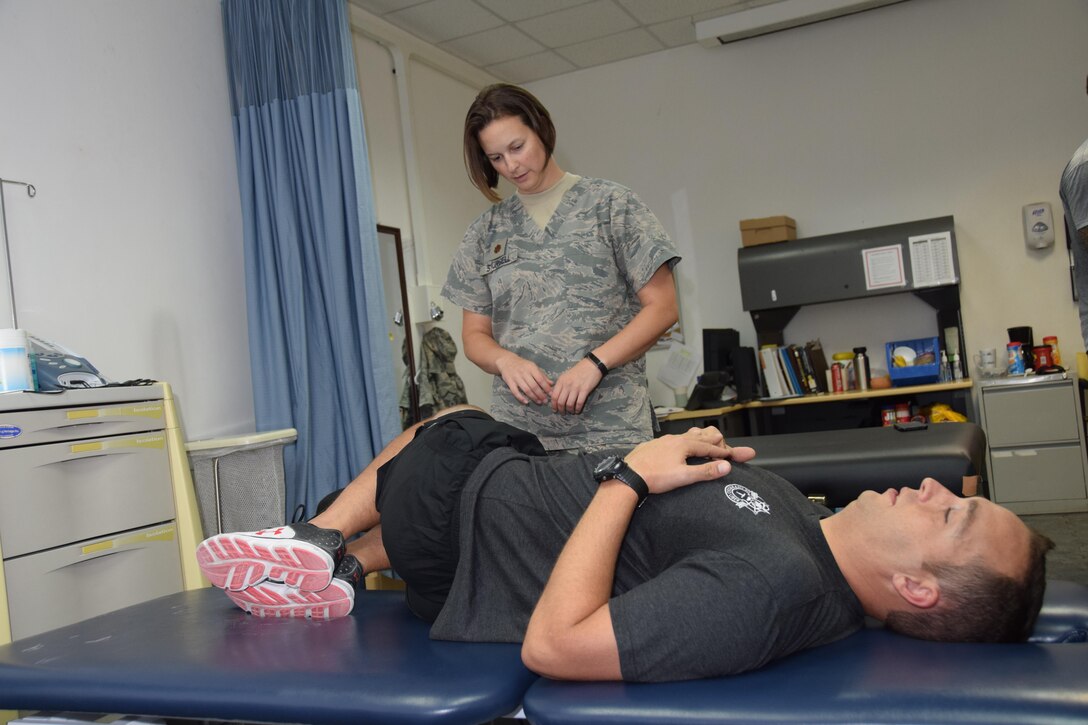 U.S. Army Staff Sgt. Andrew Childress, 8th Expeditionary Air Mobility Squadron intelligence analyst, lies on his back and works on improving his flexibility as he listens to guidance from Maj. Erin R. Sturgell, 379th Expeditionary Medical Operations Squadron physical therapist, at the Physical Therapy Clinic July 28, 2016, at Al Udeid Air Base, Qatar. The clinic’s mission is to provide injury prevention education, treat musculoskeletal injuries and get service members, like Childress, back to the fight. (U.S. Air Force photo/Technical Sgt. Carlos J. Treviño/Released)