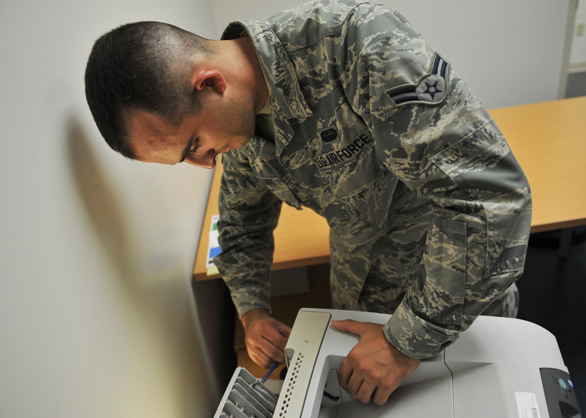 U.S. Air Force Airman 1st Class Mike Magliaro, 325th Communications Squadron client systems technician, performs maintenance on a printer in the 325th CS Annex on Tyndall Air Force Base, Fla., Aug. 3, 2016. As a new CST, Magliaro is still learning the job and is on his way to becoming a fully qualified technician. (U.S. Air Force photo by Senior Airman Dustin Mullen/Released)