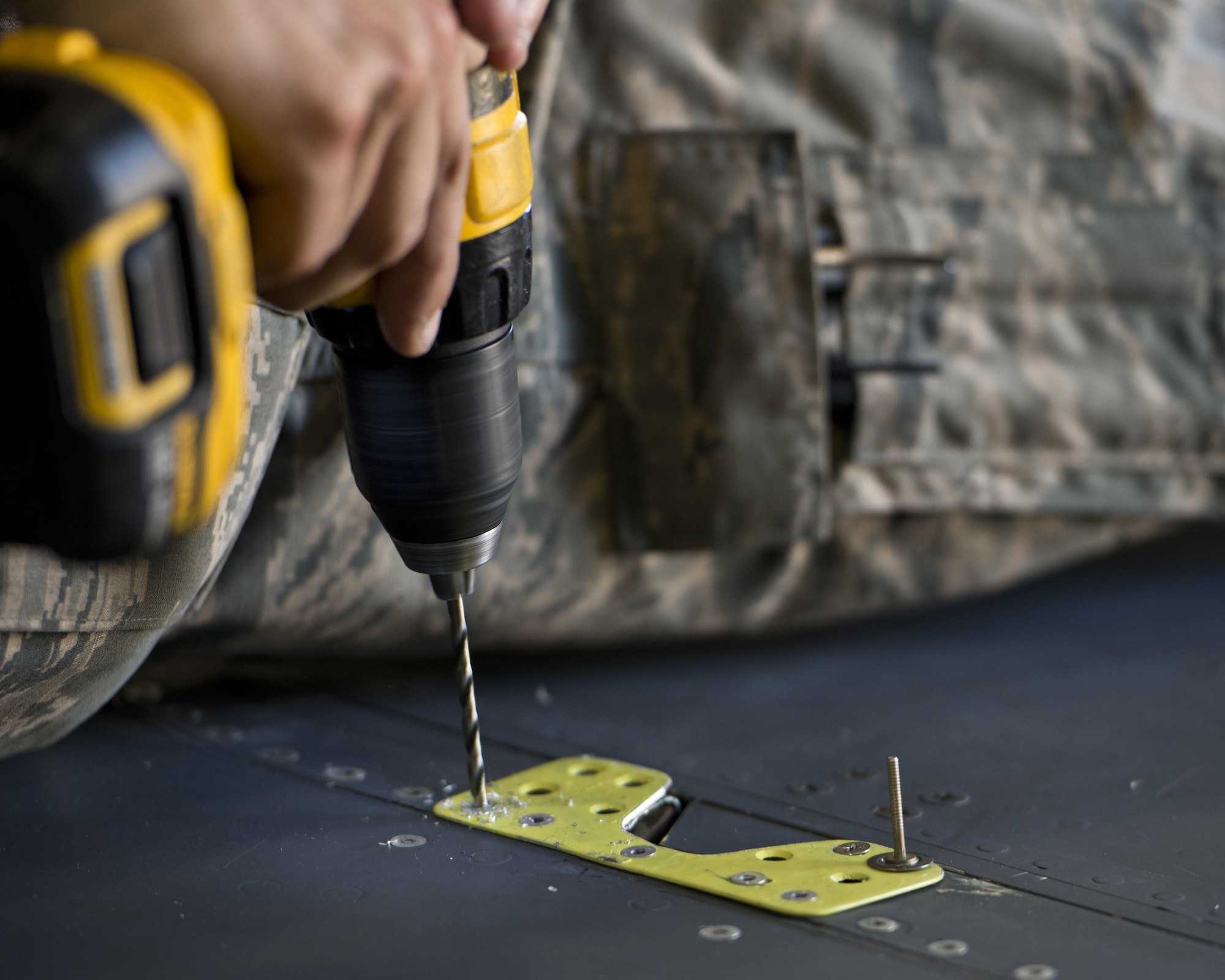 Airman 1st Class Anthony Walters, 5th Maintenance Squadron aircraft structural maintenance, drills a rivet atop the wing of a B-52H Stratofortress at Minot Air Force Base, N.D., August 2, 2016. The yellow sheet metal patches are riveted down to repair cracked spoilers on the B-52s. (U.S. Air Force photo/Airman 1st Class J.T. Armstrong)
