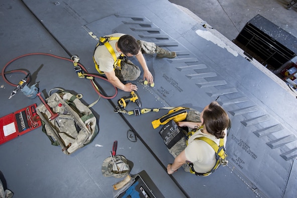 Airman 1st Class Anthony Walters and Senior Airman Amanda Scanlan, 5th Maintenance Squadron aircraft structural maintenance, repair a spoiler atop the wing of a B-52H Stratofortress at Minot Air Force Base, N.D., August 2, 2016. Scanlan instructs Walters on how to patch cracked spoilers as a part of on-the-job training. (U.S. Air Force photo/Airman 1st Class J.T. Armstrong)