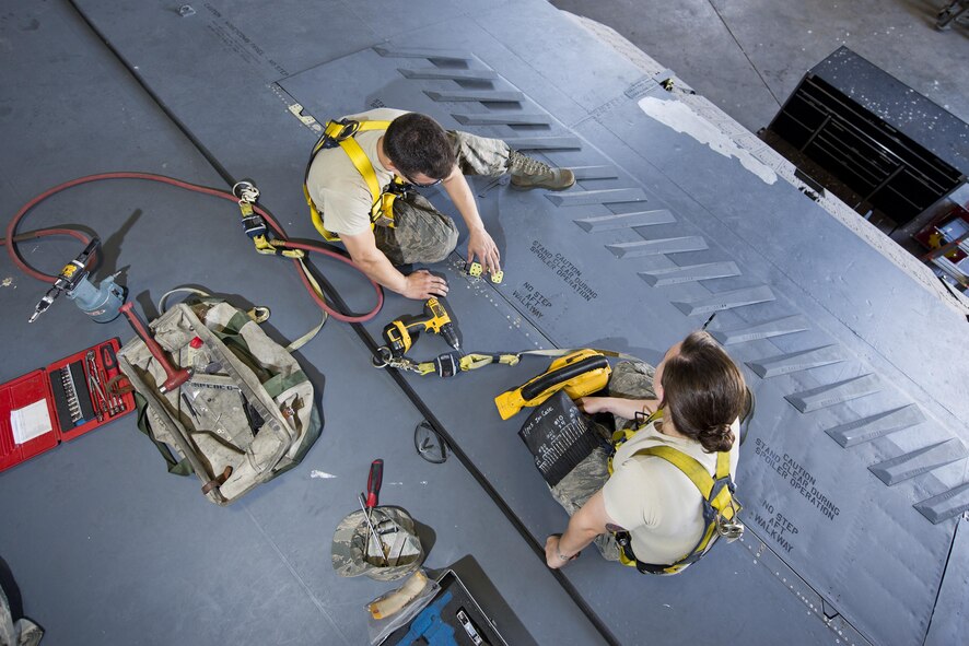 Airman 1st Class Anthony Walters and Senior Airman Amanda Scanlan, 5th Maintenance Squadron aircraft structural maintenance, repair a spoiler atop the wing of a B-52H Stratofortress at Minot Air Force Base, N.D., August 2, 2016. Scanlan instructs Walters on how to patch cracked spoilers as a part of on-the-job training. (U.S. Air Force photo/Airman 1st Class J.T. Armstrong)