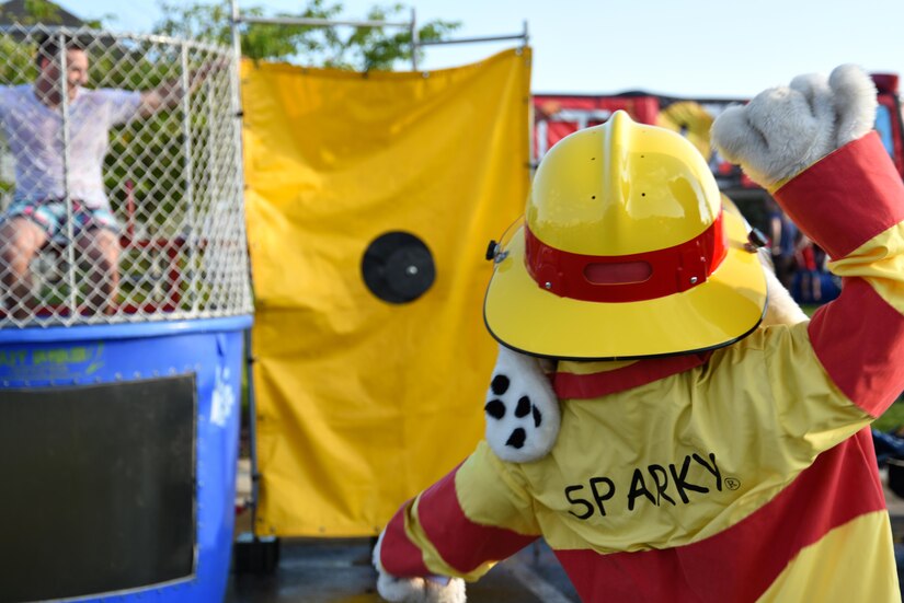 Sparky the Fire Dog, official mascot of the National Protection Association, attempts to dunk Senior Airman Brandon Thompson, 11th Security Forces Squadron unit facility manager, during a National Night Out event held at the Liberty Park welcome center on Joint Base Andrews, Md., Aug. 2, 2016. The event had demonstrations from various units on base, including the 11th Civil Engineer Squadron Fire Department and 11th SFS. (U.S. Air Force photo by Airman Gabrielle Spalding)