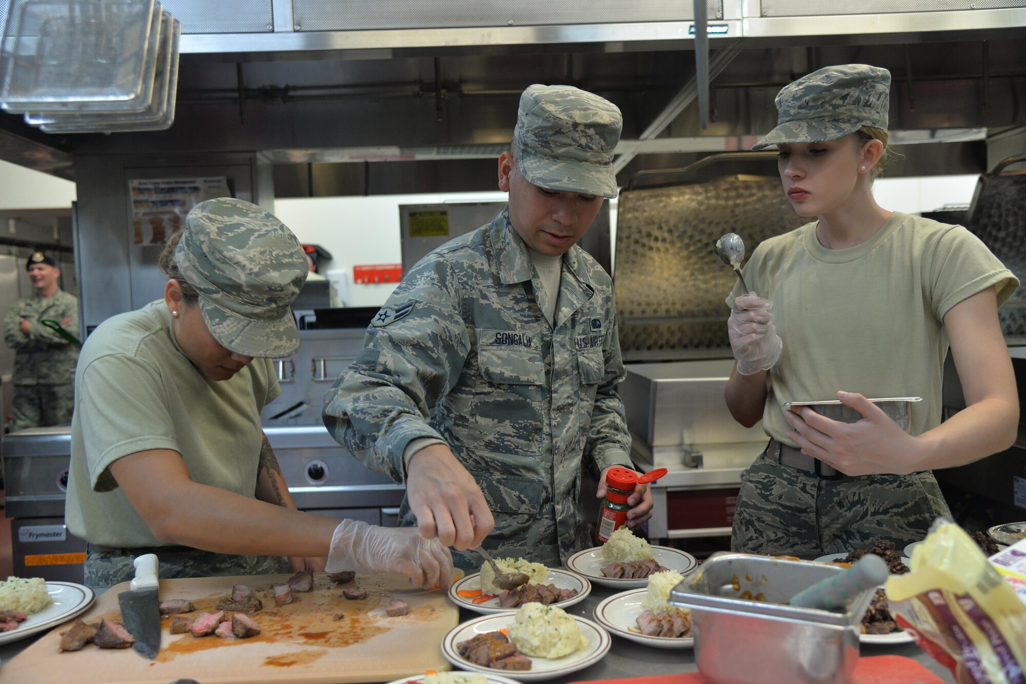 Airmen 1st Class Lekeya Lindsey, left, Nikko Songalia, center, and Alisha Hubbard, 341st Force Support Squadron missile chefs, prepare their dishes during the Warrior Chef competition Aug. 3, 2016, at Malmstrom Air Force Base, Mont. Each team had one hour to prepare three dishes to be critiqued by five judges. (U.S. Air Force photo/Airman 1st Class Daniel Brosam)