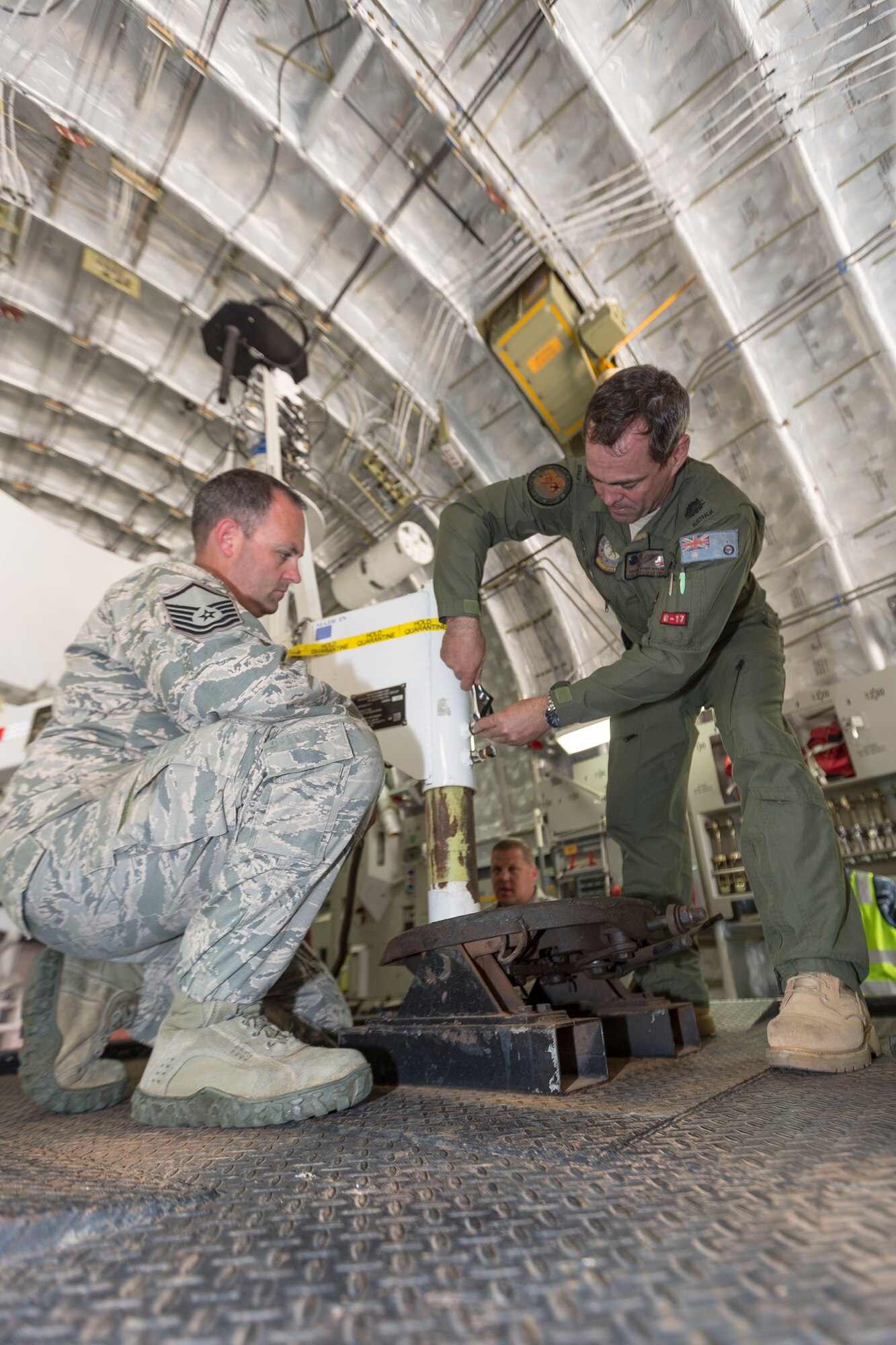 U.S. Air Force Master Sgt. Donald Taylor, with the 266th Range Squadron, deployed from Mountain Home Air Force Base, Idaho, and Royal Australian Air Force (RAAF) Warrant Officer Dwayne Taylor, with No 36 Squadron, prepare to lower a trailer to the hitch on board a C-17A during Pitch Black 16, in Darwin, Australia, Aug. 2, 2016. Pitch Black is a biennial multinational air warfare exercise hosted by the RAAF that focuses on offensive counter air and defensive counter air combat in a simulated war environment. (Australian Defence Force photo by Cpl. David Gibbs)