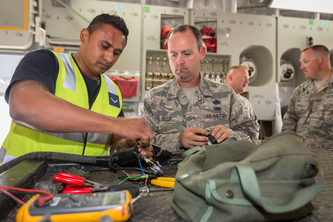 Leading Aircraftman Nitin Naidu (left), an Avionics Technician assigned to No 36 Squadron, strips electrical wire for a plug with the help of a U.S. Airman during Pitch Black 16, in Darwin, Australia, Aug. 2, 2016. Pitch Black is a biennial multinational air warfare exercise hosted by the Royal Australian Air Force that focuses on offensive counter air and defensive counter air combat in a simulated war environment. (Australian Defence Force photo by Cpl. David Gibbs)