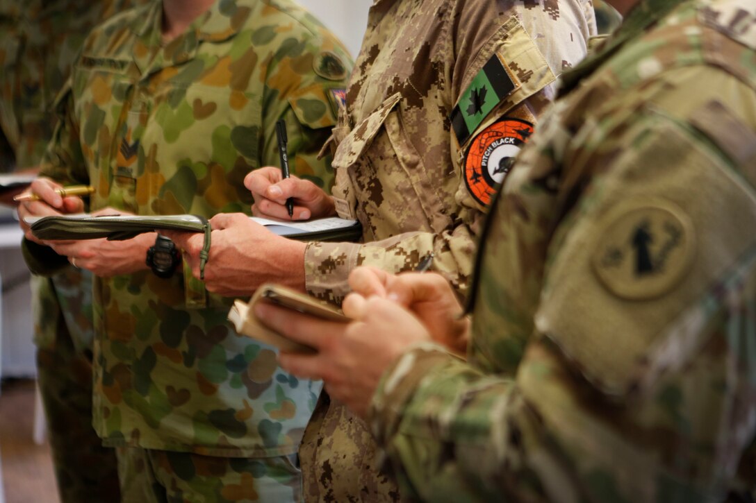 Military members from Australia, Canada and the United States take notes during a Pitch Black 16 mission briefing in Darwin, Australia, Aug. 2, 2016. Pitch Black is a biennial multinational air warfare exercise hosted by the Royal Australian Air Force that focuses on offensive counter air and defensive counter air combat in a simulated war environment. (Australian Defence Force photo by Cpl. Casey Gaul)