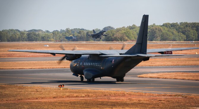 A French CN235 aircraft taxis as a U.S. Air Force F-16 aircraft takes off during exercise PITCH BLACK (PB16) at Royal Australian Air Force (RAAF) Base Darwin, Australia, Aug. 1, 2016. PB16 allows participant nations to exercise deployed units in the tasking, planning and execution of Offensive Counter Air and Offensive Air Support while utilizing one of the largest training airspace areas in the world.  The exercise is scheduled from July 29 to Aug.19, 2016.(Australian Defence Force photo by Cpl. Casey Gaul)