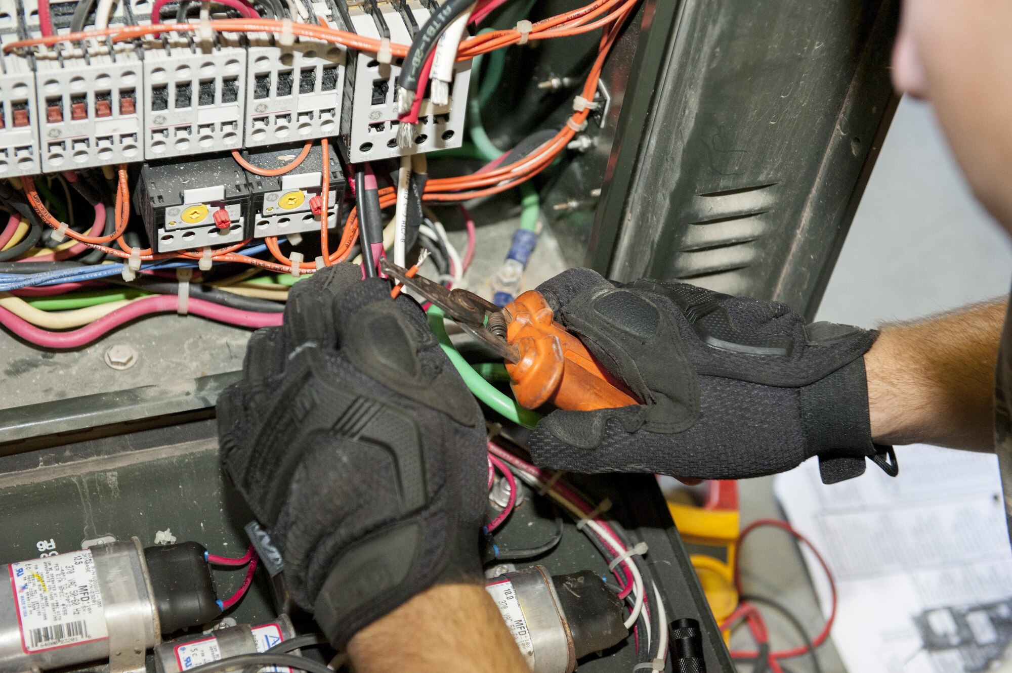 U.S. Air Force Senior Airman Todd Gonsalves, 786th Civil Engineer Squadron heating, ventilation and air conditioning journeyman, uses a wire stripper to remove the protective coating from electrical wires while repairing an air conditioning unit July 28, 2016, at Incirlik Air Base, Turkey. Gonsalves came to Incirlik Air Base on temporary duty to augment and support the continuous operations supporting Operation Inherent Resolve. (U.S. Air Force photo by Staff Sgt. Jack Sanders)