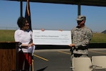 Betsy Kauffman, with Energy Trust of Oregon, presents a check for $84,319 to Col. Kenneth Safe, construction and facilities management officer for the Oregon Army National Guard, as part of the dedication of the Oregon Military Department's new solar panel array at the Oregon Army National Guard's Army Aviation Support Facility (AASF #2) at the airport in Pendleton, Oregon, August 4. The Oregon Military Department partnered with Energy Trust of Oregon, the federal government and Pacific Power to bring the project to completion, working toward the larger goal of making the Oregon National Guard net zero by 2020.