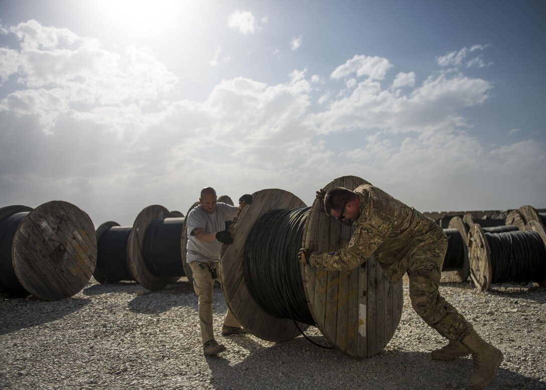 Staff Sgt. Corey Blanar, 455th Expeditionary Communications Squadron, cable and antenna maintenance noncommissioned officer in charge and Patrick Casket, 455th Expeditionary Communications Squadron, cable and antenna maintenance technician, roll a cable reel, Bagram Airfield, Afghanistan, July 30, 2016. The cable team ensures that all cable and wireless systems are installed and maintained and provide command and control (C2) capabilities throughout the base. (U.S. Air Force photo by Senior Airman Justyn M. Freeman)
