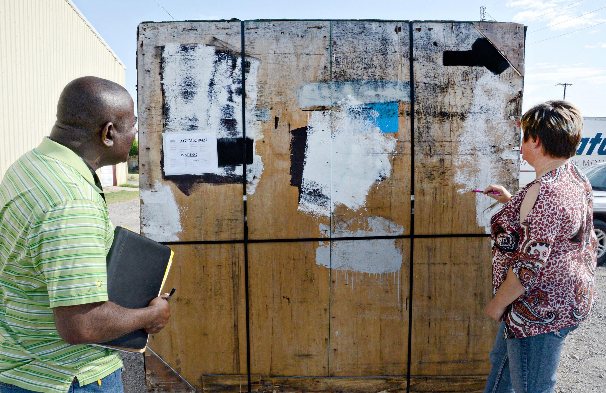 Ronald Jackson and Marsha Whitmire, quality assurance inspectors with the 72nd Logistics Readiness Squadron, inspect a moldy pallet at the business location of a local moving company. The company had received the pallet in less-than-desirable condition and immediately notified the Personal Property and Passenger Movement Section. Inspectors have to be on-site when the pallet is opened to be able to observe the condition of the contents inside and make a determination of what their next step will be. (Air Force photo by Kelly White)