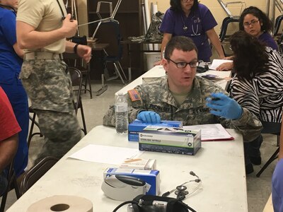 U.S. Army Reserve Sgt. Kyle Puchalsky, a health care specialist with the 405th Combat Support Hospital, speaks with a patient during Operation Lone Star at Vela Middle School in Brownsville, Texas July 25, 2016.  Operation Lone Star is one of the Innovative Readiness Training events in a joint effort between the Texas Department of State Health Services, the Texas State Guard and the U.S. Army Reserve, which provides real-world training in a joint civil-military environment while delivering world class medical care to the people of south Texas from July 25-29, 2016. (U.S. Army photo by Staff Sgt. Syreeta Shaw/released)