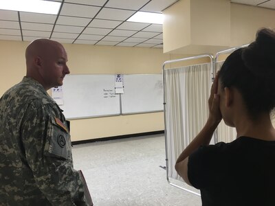 U.S. Army Reserve Staff Sgt. Josh Pelletier, a health care specialist with the 399th Combat Support Hospital, has a patient read an eye chart during Operation Lone Star at Vela Middle School in Brownsville, Texas July 25, 2016.  Operation Lone Star is one of the Innovative Readiness Training events in a joint effort between the Texas Department of State Health Services, the Texas State Guard and the U.S. Army Reserve, which provides real-world training in a joint civil-military environment while delivering world class medical care to the people of south Texas from July 25-29, 2016. (U.S. Army photo by Staff Sgt. Syreeta Shaw/released)