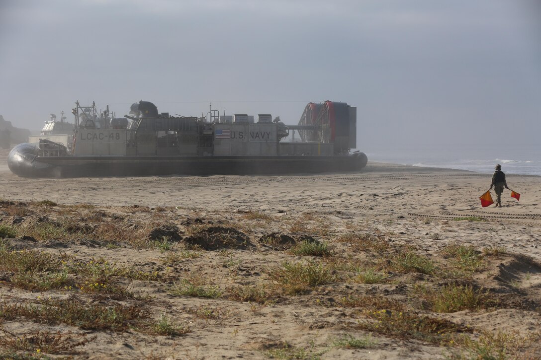 A U.S. Navy Sailor signals a Landing Craft Air Cushion with Assault Craft Unit 5 during amphibious assault training on Camp Pendleton, Calif., August 2, 2016. The LCAC carries cargo, vehicles like high mobility multi-purpose wheeled vehicles and M1A1 Abrams tanks, and personnel for ship to shore movements.  (U.S. Marine Corps photo by Lance Cpl. Shellie Hall)