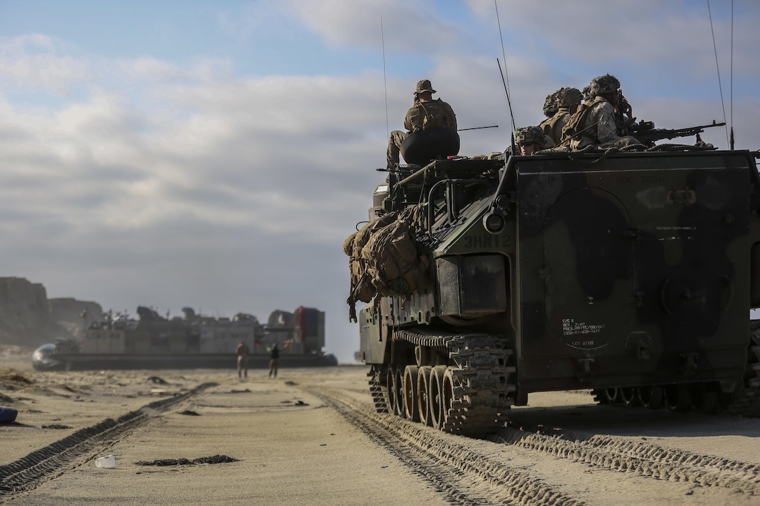 Marines of 3rd Battalion 1st Marine Regiment look out from the top of 3rd Amphibious Assault Battalion Assault Amphibious Vehicle as a Landing Craft Air Cushion with Navy Assault Craft Unit 5, comes ashore bringing vehicles and Marines aboard Marine Corps Base Camp Pendleton, Calif., Aug. 2, 2016. This amphibious assault was part of 3rd Battalion’s Marine Corps Combat Readiness Evaluation that will prepare the Marines for their upcoming Deployment. (U.S. Marine Corps photo by Cpl. Timothy Valero/ Released)