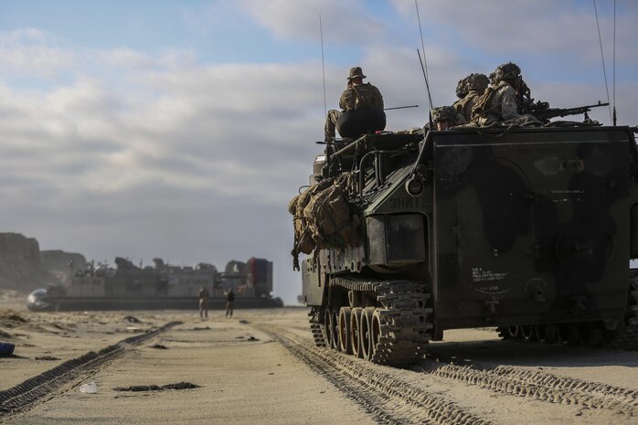 Marines of 3rd Battalion 1st Marine Regiment look out from the top of 3rd Amphibious Assault Battalion Assault Amphibious Vehicle as a Landing Craft Air Cushion with Navy Assault Craft Unit 5, comes ashore bringing vehicles and Marines aboard Marine Corps Base Camp Pendleton, Calif., Aug. 2, 2016. This amphibious assault was part of 3rd Battalion’s Marine Corps Combat Readiness Evaluation that will prepare the Marines for their upcoming Deployment. (U.S. Marine Corps photo by Cpl. Timothy Valero/ Released)