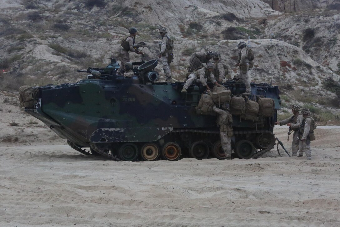 Marines with 3rd Battalion, 1st Marine Regiment, 1st Marine Division attach packs to the outside of an amphibious assault vehicle during a Marine Corps Combat Readiness Evaluation on Camp Pendleton, Calif., August 2, 2016. After navigating through the ocean on amphibious assault vehicles, the Marines moved inland with high mobility multi-purpose wheeled vehicles and M1A1 Abrams tanks to reach their objective. (U.S. Marine Corps photo by Lance Cpl. Shellie Hall)