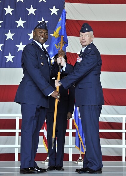 Col. Rodney Lewis, 319th Air Base Wing commander, hands the 319th Mission Support Group guidon to Col. Michal Holiday, the new 319th MSG commander, during a change of command ceremony on Grand Forks Air Force Base, N.D., Aug. 05, 2016. Holiday assumed command from Col. Anthony Hernandez. (U.S. Air Force photo by Senior Airman Xavier Navarro/Released)