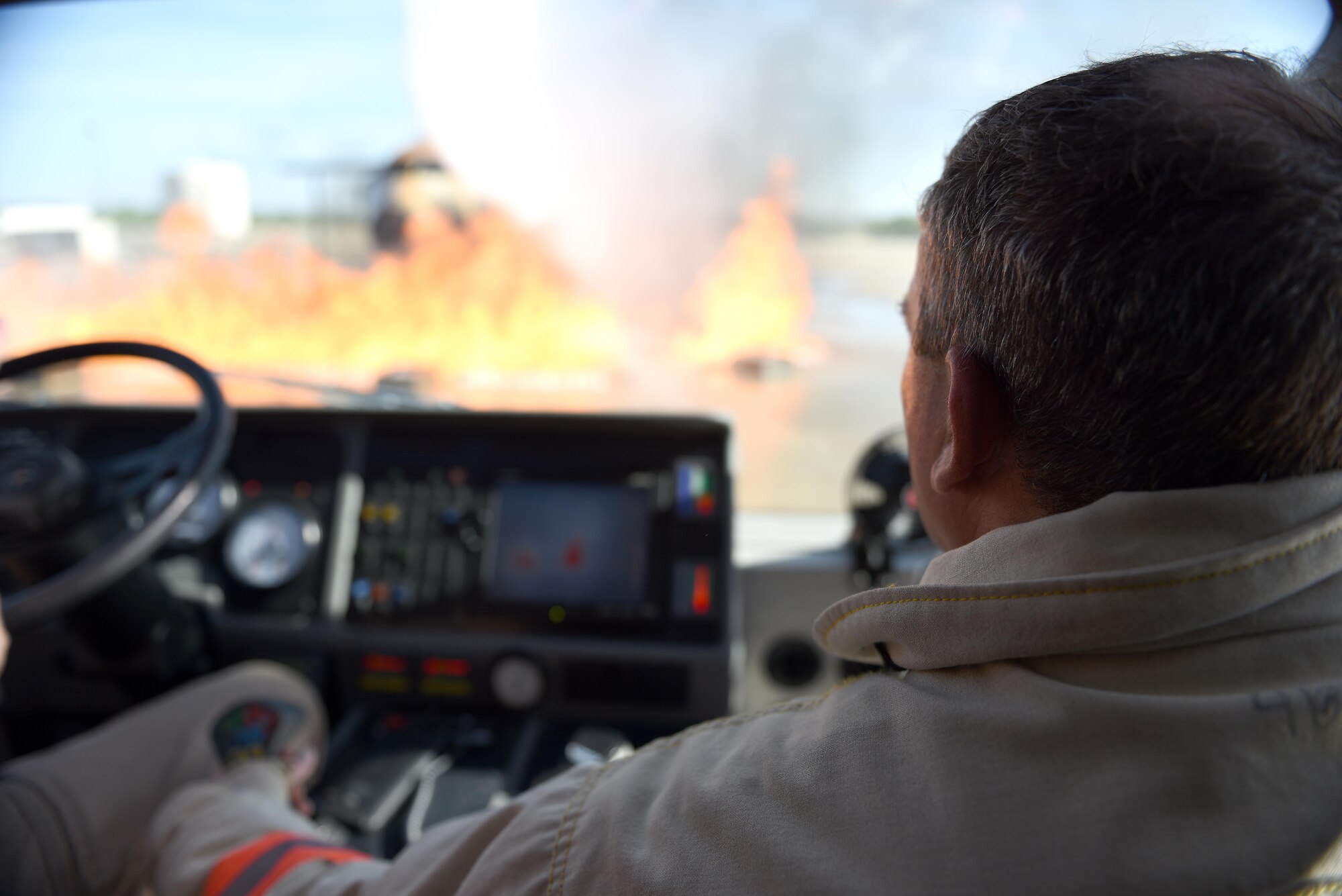U.S. Air Force Lt. Col. Garrett Stumb, 315th Civil Engineer Squadron Commander, Joint Base Charleston, extinguishes flames using a remote operated hose attached to the roof of a heavy duty firetruck during the Fire Marshall course at the Louis F. Garland Department of Defense Fire Academy on Goodfellow Air Force Base, Texas, Aug. 3, 2016. For training purposes, the fire is ignited in specific areas using propane to simulate an aircraft fuel fire. (U.S. Air Force photo by Airman 1st Class Caelynn Ferguson/Released)