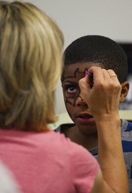 A volunteer paints the face of six year-old Roderick Burse, at an anti-bullying event called Stop Bullying, Give Peace a Chance, held inside the Religious Education Facility at Wright-Patterson Air Force Base, Ohio, Aug. 2, 2016. Burse is the son of Ronneja and Staff Sgt. Roderick Burse Jr., 435th Supply Chain Operations Squadron. (U.S. Air Force photo/R.J. Oriez)
