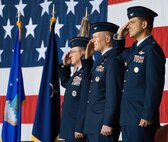 Brig. Gen. Patrick Mordente, 18th Air Force vice commander, left, Col. Michael Grismer, 436th Airlift Wing commander, center, and Col. Ethan Griffin, right, salute the U.S. flag during the singing of the national anthem Aug. 5, 2016, inside Hangar 706, on Dover Air Force Base, Del. The 436th Airlift Wing held a change of command ceremony officiated by Mordente. (U.S. Air Force photo/Roland Balik)